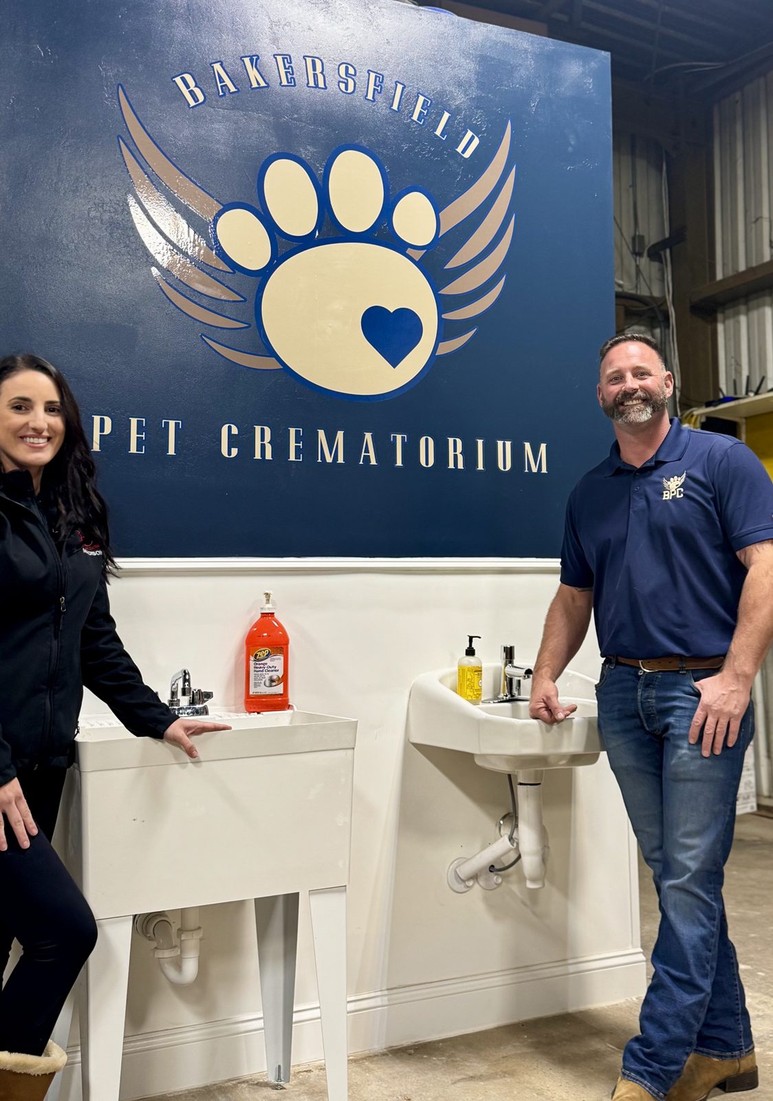 The Bakersfield Pet Crematory team beside the crematorium's paw-print logo wall